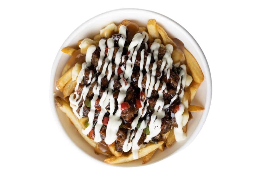 A bowl of fries loaded with donair meat, gravy, curds, diced peppers and a garlic sauce drizzle.